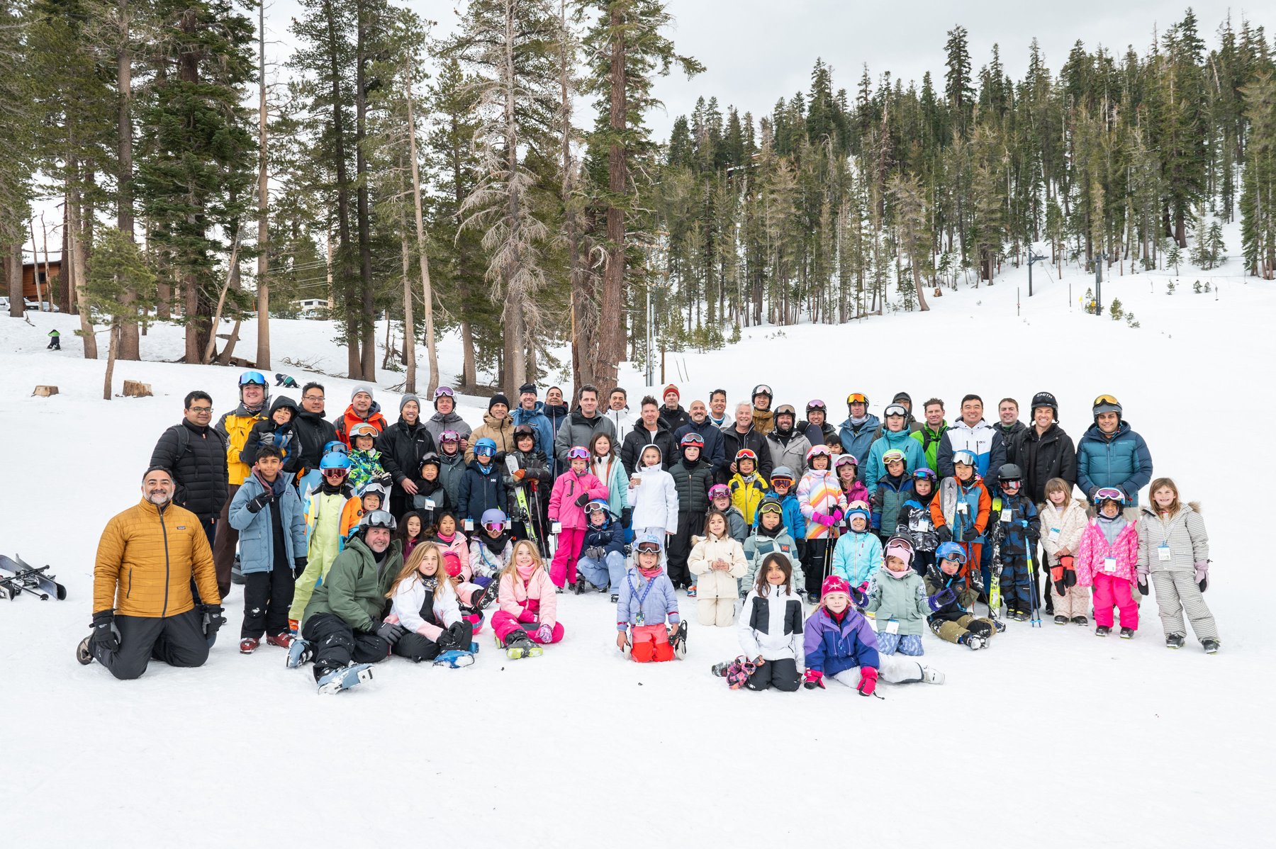 Dads and children gather in ski gear among snowy trees at Mammoth