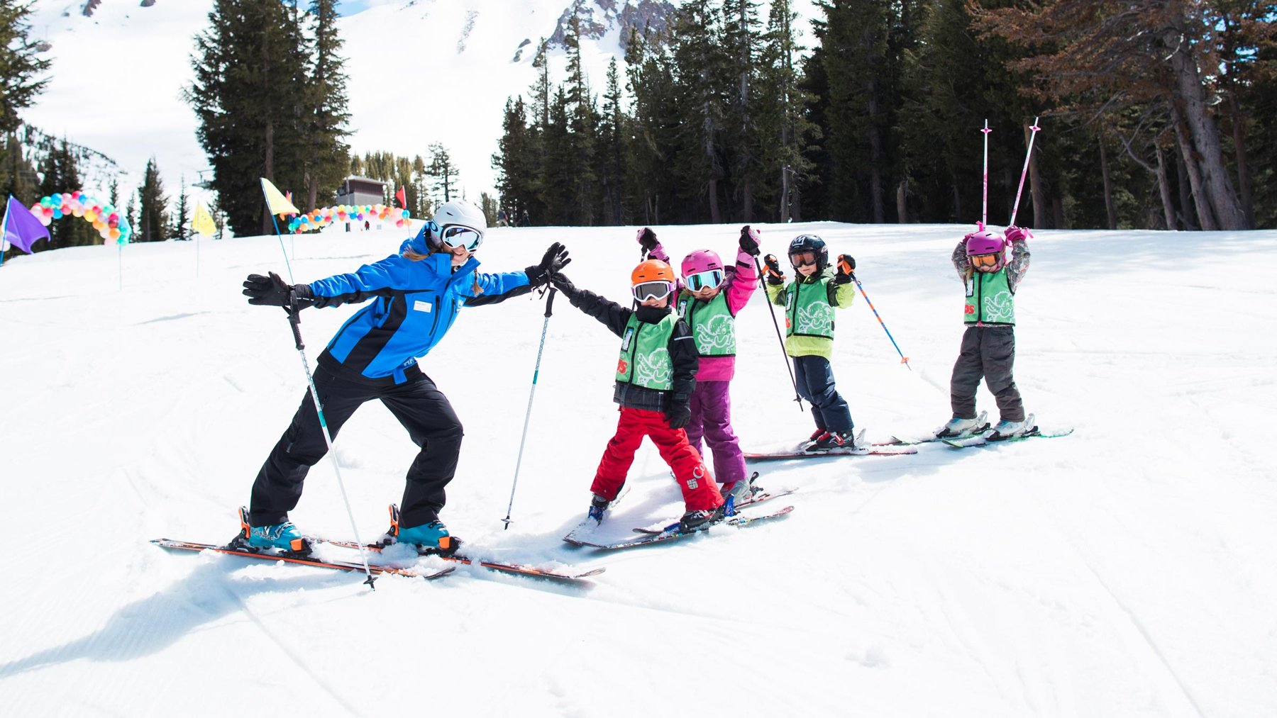 A ski instructor high-fives children at a Mammoth Mountain lesson